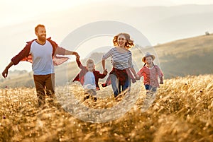 Happy family: mother, father, children son and daughter runing and jumping on sunset