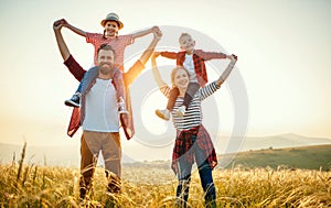 Happy family: mother, father, children son and daughter standing and hugging on sunset