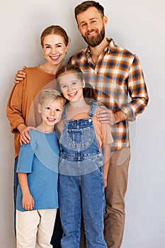 Happy family mother father and children standing against empty grey wall