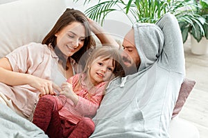 Happy family Mother father and daughter lie in bed rest hugging and having fun Play Tickle. Parenting in Morning routine
