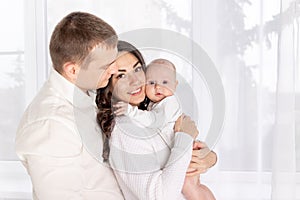 Happy family mother and father hold a newborn baby at home, the concept of happy loving family, lifestyle