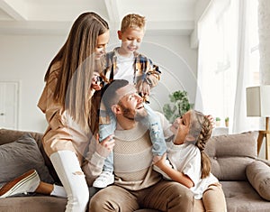 Happy family mother father and kids having fun at home on couch