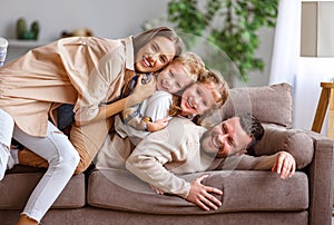 Happy family mother father and kids having fun at home on couch