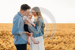 Happy family, mother, father and little child on the ripe wheat field