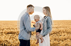 Happy family, mother, father and little child on the ripe wheat field