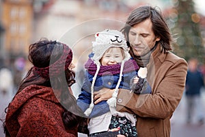 Happy Family - mother, father and little girl walking in autumn city and having fun