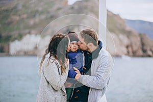 Happy family -mother, father and little son- walking in harbour