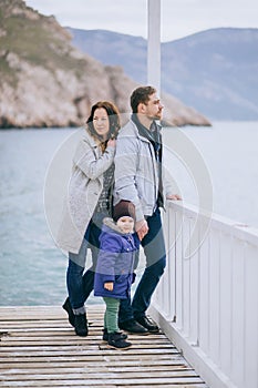 Happy family -mother, father and little son- walking in harbour