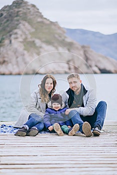 Happy family -mother, father and little son- walking in harbour