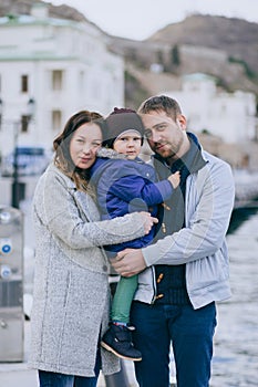 Happy family -mother, father and little son- walking in harbour