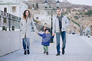 Happy family -mother, father and little son- walking in harbour