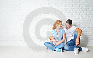 happy family mother, father of a newborn baby on floor near blank wall