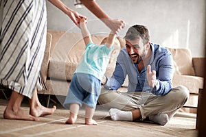 Happy family mother and father playing with a baby at home