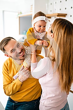 Happy family mother and father playing with a baby at home