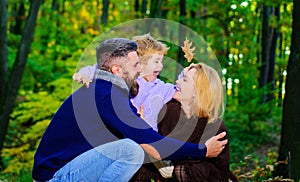 Happy family. Mother, father and son on autumn walk in park. Parents and child relaxing together in sunny day.