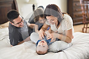 Happy family mother, father and two children at home in bed