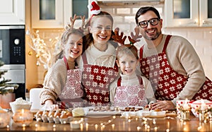 Happy family mother, father, two kids baking Christmas cookies in kitchen