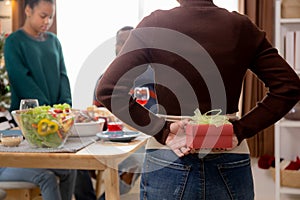 Happy family with mother giving gift box with daughter during dinner at home.