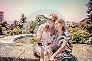 Happy family mother and her adorable little daughter on summer vacation taking selfie with smartphone