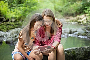 Happy family mother and her adorable little daughter on summer vacation taking selfie with smartphone