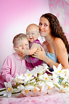 Happy family mother and her children boy and girl sitting indoor