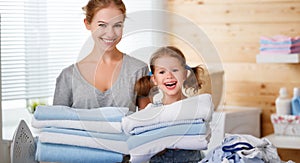 Happy family mother housewife and child daughter ironing clothes