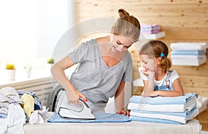 Happy family mother housewife and child daughter ironing clothes