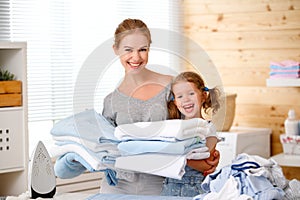 Happy family mother housewife and child daughter ironing clothes