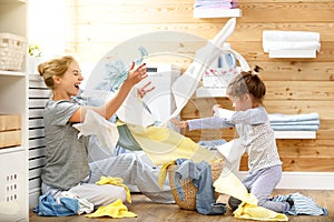 Happy family mother housewife and child in laundry with washin