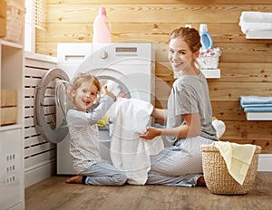 Happy family mother housewife and child in laundry with washin