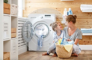 Happy family mother housewife and child in laundry with washin