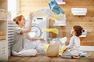 Happy family mother housewife and child in laundry with washin