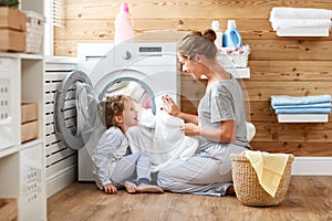 Happy family mother housewife and child in laundry with washin