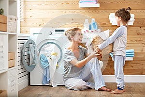 Happy family mother housewife and child in laundry with washin