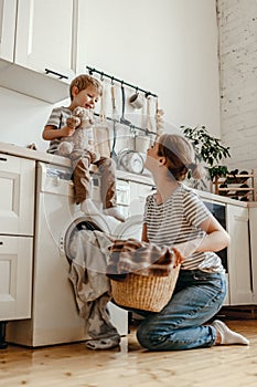 Happy family mother housewife and child   in laundry with washing machine