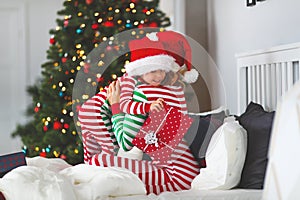 Happy family mother hug her baby son in pajamas opening gifts o