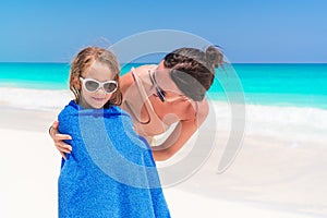 Happy family of mother and kid on the beach vacation. Little girl in towel on the seashore