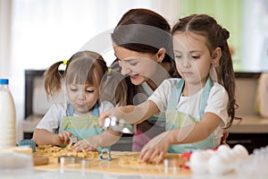 Happy family mother and kids are preparing the dough, bake cookies in the kitchen