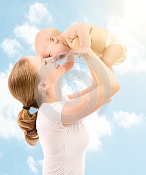 Happy family. Mother kissing baby in the sky