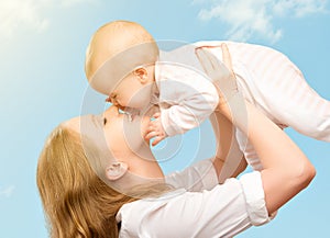 Happy family. Mother kissing baby in the sky