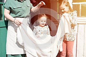 Happy family mother with little kids daughters helper girls have fun in suburb countryside life on laundry day. candid mom and chi