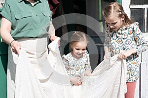 Happy family mother with little kids daughters helper girls have fun in suburb countryside life on sunny laundry day. candid mom a