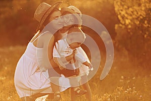 Happy family of mother, little son and daughter spending free time on the field at sunny day time of summer