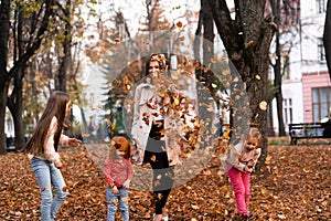Happy family. mother of many children and three daughters child girl together, playing with dry autumn leaves , joyfully