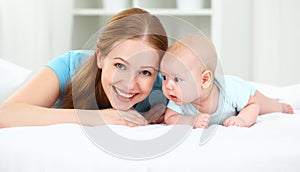 Happy family mother playing with baby in bed