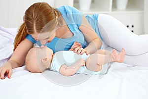 Happy family mother playing with baby in bed