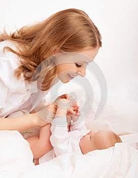 Happy family. mother playing with her baby in bed