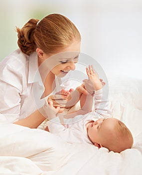 Happy family. mother playing with her baby in bed