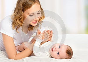 Happy family. mother playing with her baby in bed