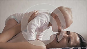 Happy family. mother playing with her baby in the bedroom. Laughing and smiling.